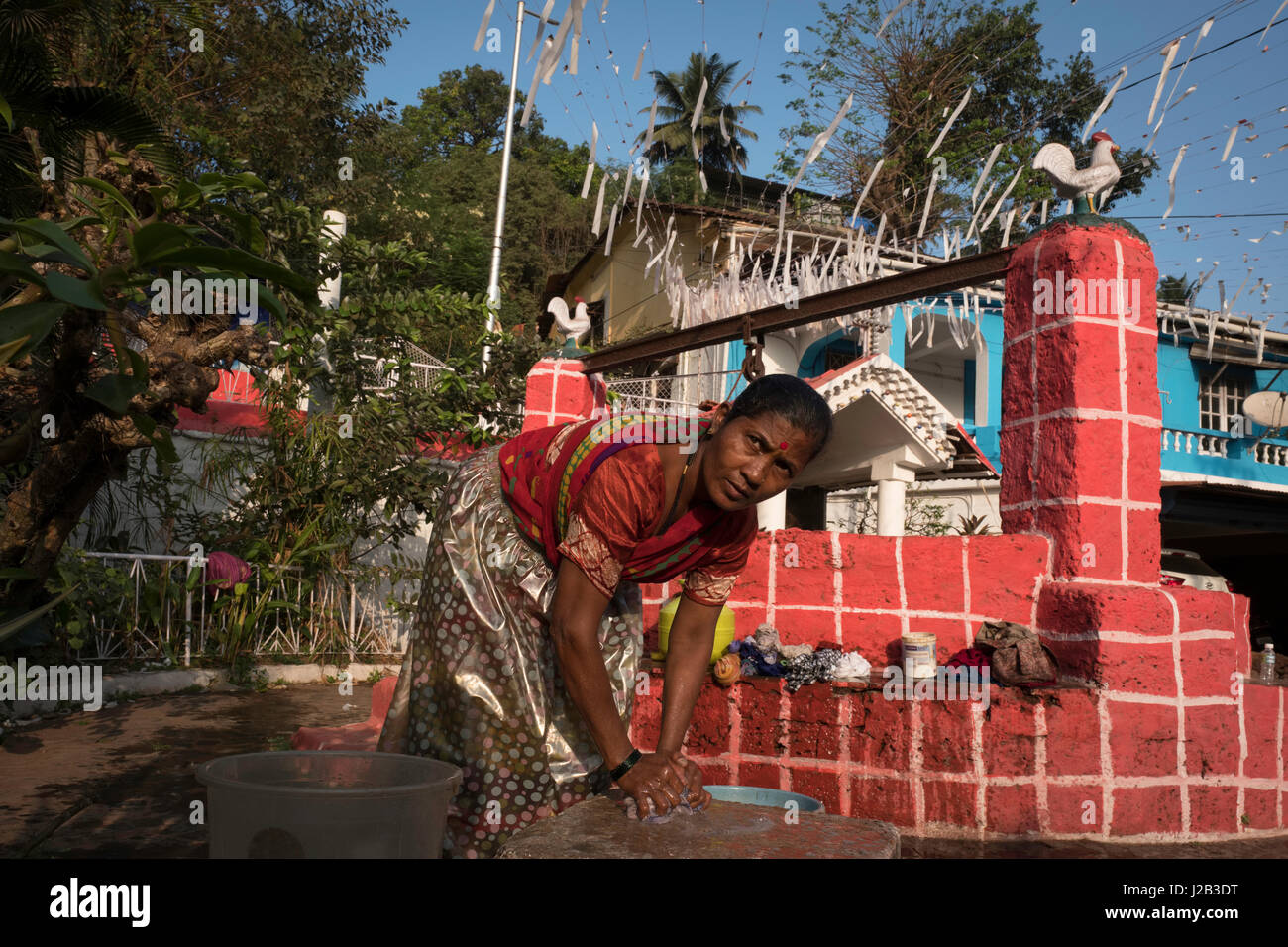 Una donna abiti da lavaggi con acqua ottenuta da un pozzo Foto Stock