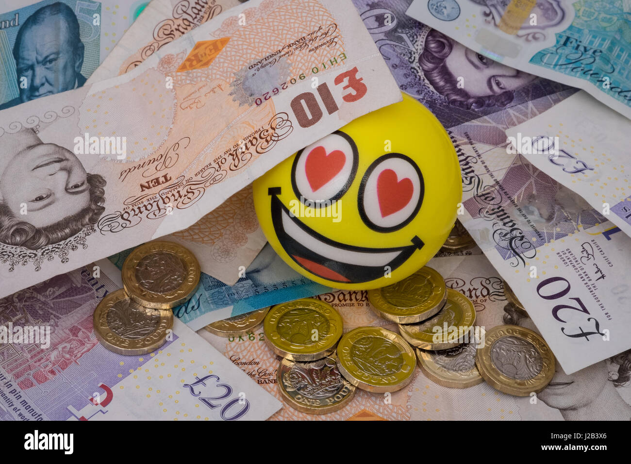 Felice di emoji a volto coperto nel Regno Unito i soldi delle monete e delle banconote in euro Foto Stock