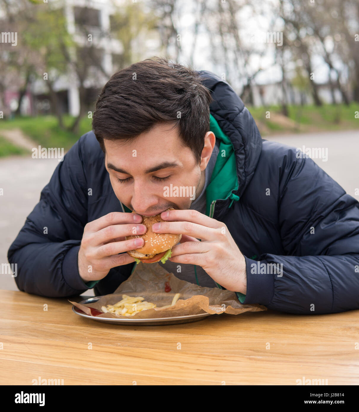L'uomo mangiare molto gustosa burger in street food cafe Foto Stock
