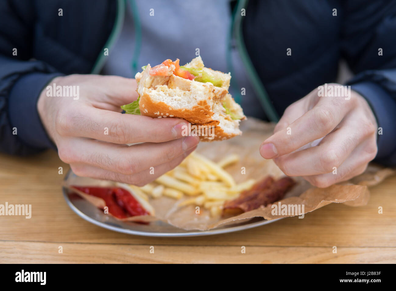 Uomo di mani morso burger in uno snack bar Foto Stock