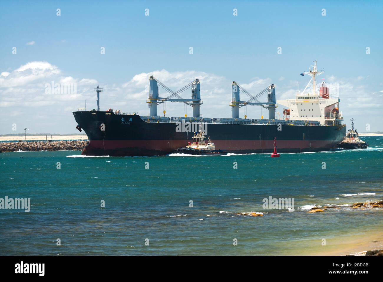 Una grande nave di carbone passa Nobbys testa come si lascia l'Oceano Pacifico ed entra nel porto di Newcastle e il Cacciatore estuario del fiume, NSW, Australia. Foto Stock