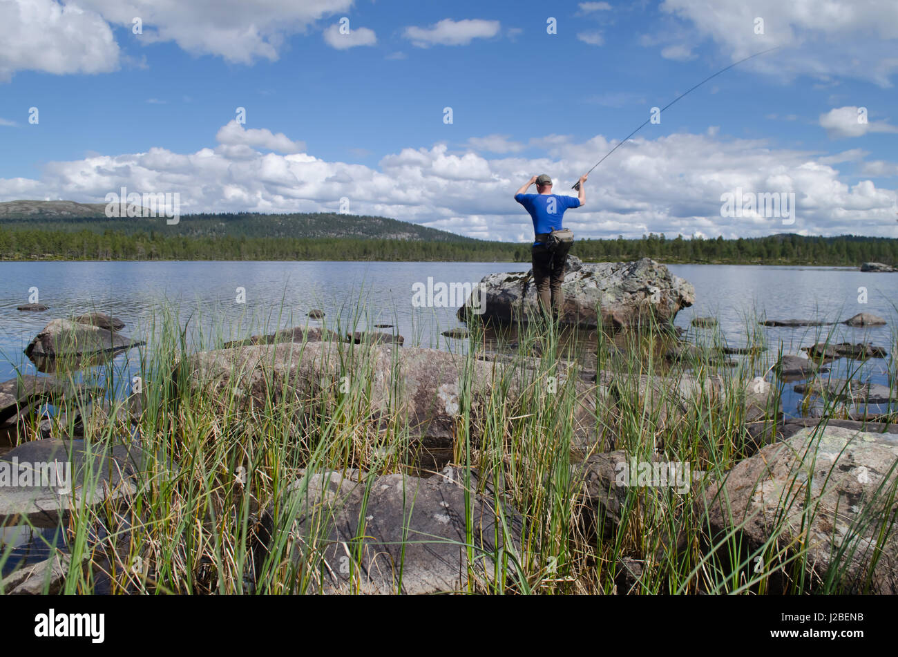 L uomo dal di dietro di Pesca a Mosca Report di Pesca lago prealpino sul giorno di estate Foto Stock