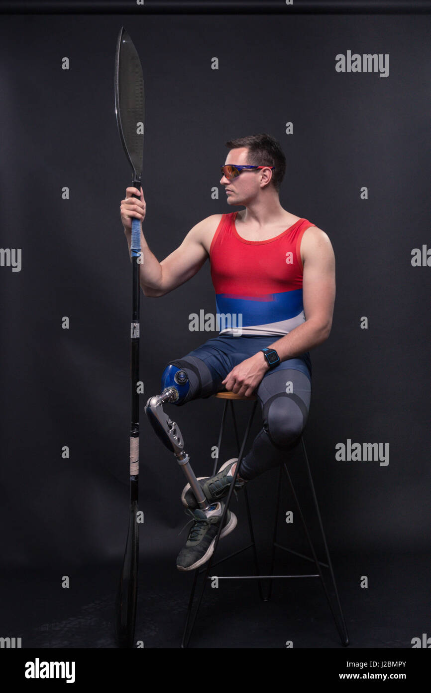 Un giovane uomo adulto solo, in seduta sgabello da bar, atleta sporstman canoe kayak paddle, gamba protesico, disattivato Foto Stock
