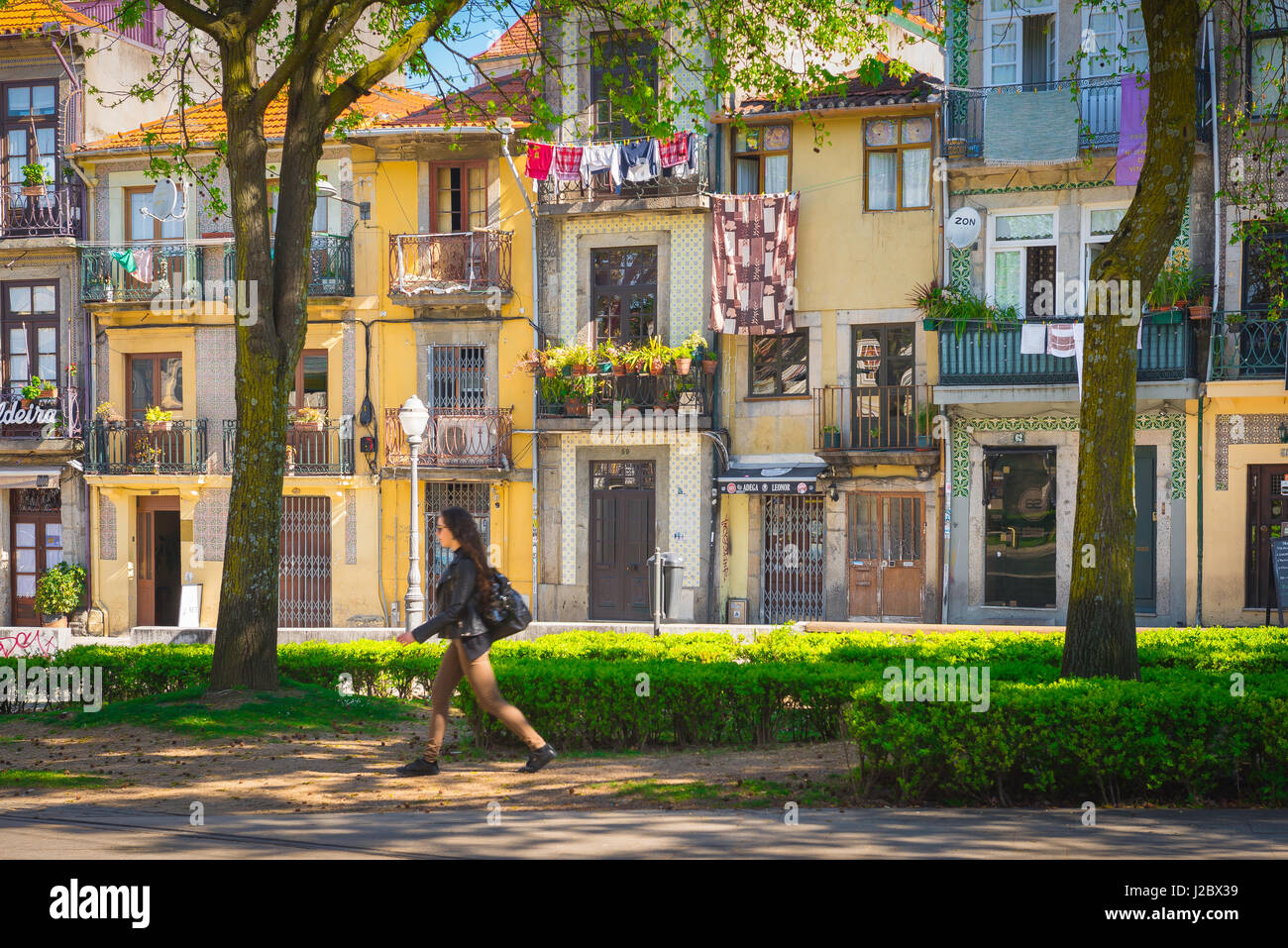 Porto Portogallo parco, vista di una donna che cammina attraverso i giardini Cordoaria, passato una strada che contiene una fila di colorate case a schiera, Porto Europe. Foto Stock