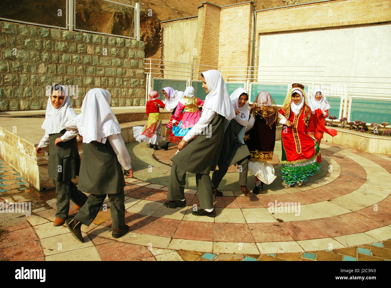 Iran, Teheran, gruppo di gioiosa ragazze ballando e saltando come uccelli in abito tradizionale (MR) Foto Stock