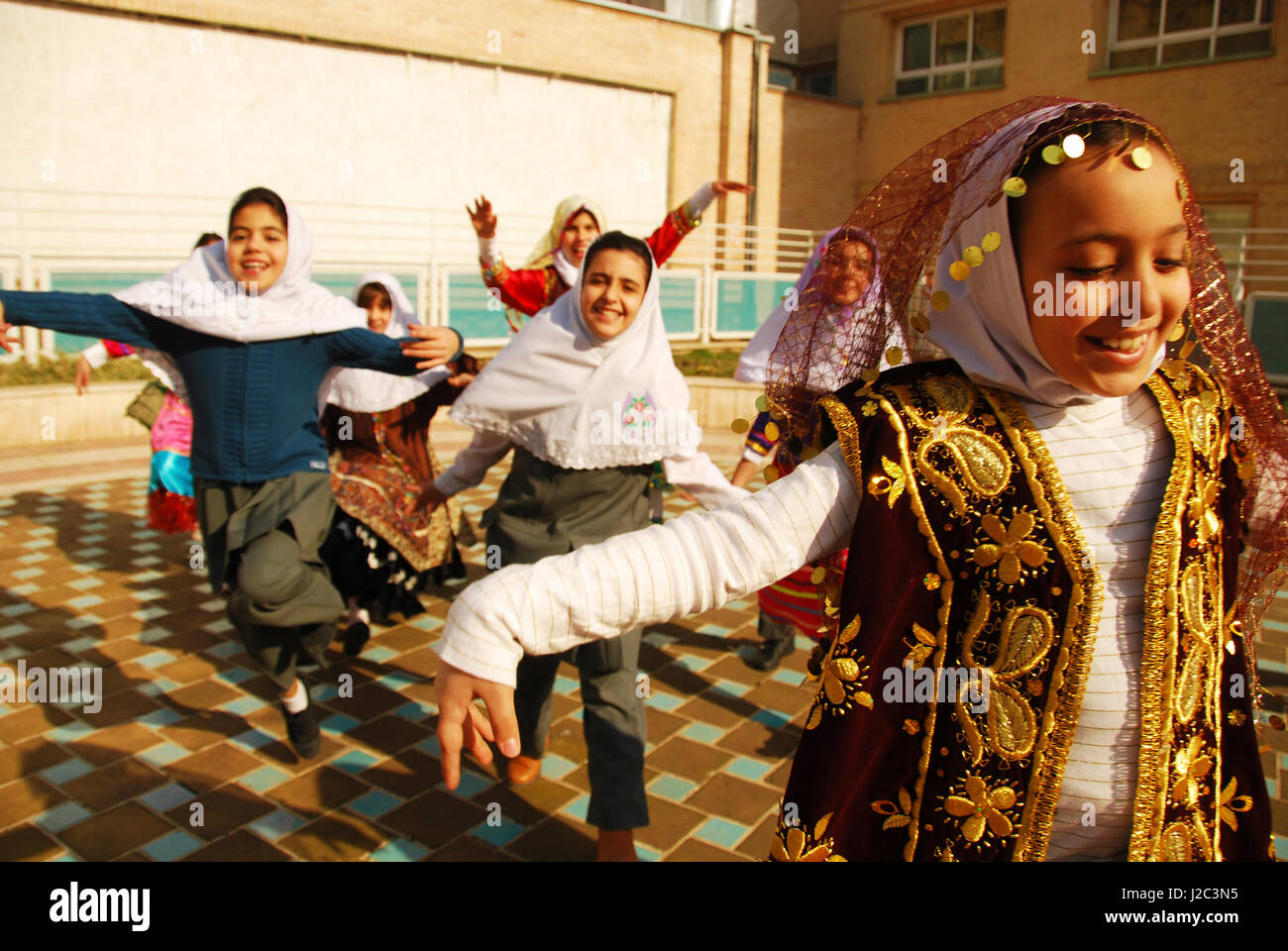 Iran, Teheran, gruppo di gioiosa ragazze correre e saltare come uccelli in abito tradizionale (MR) Foto Stock