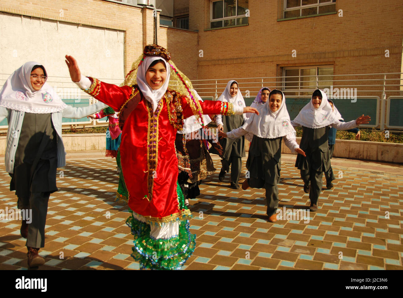 Iran, Teheran, gruppo di gioiosa ragazze correre e saltare come uccelli in abito tradizionale (MR) Foto Stock