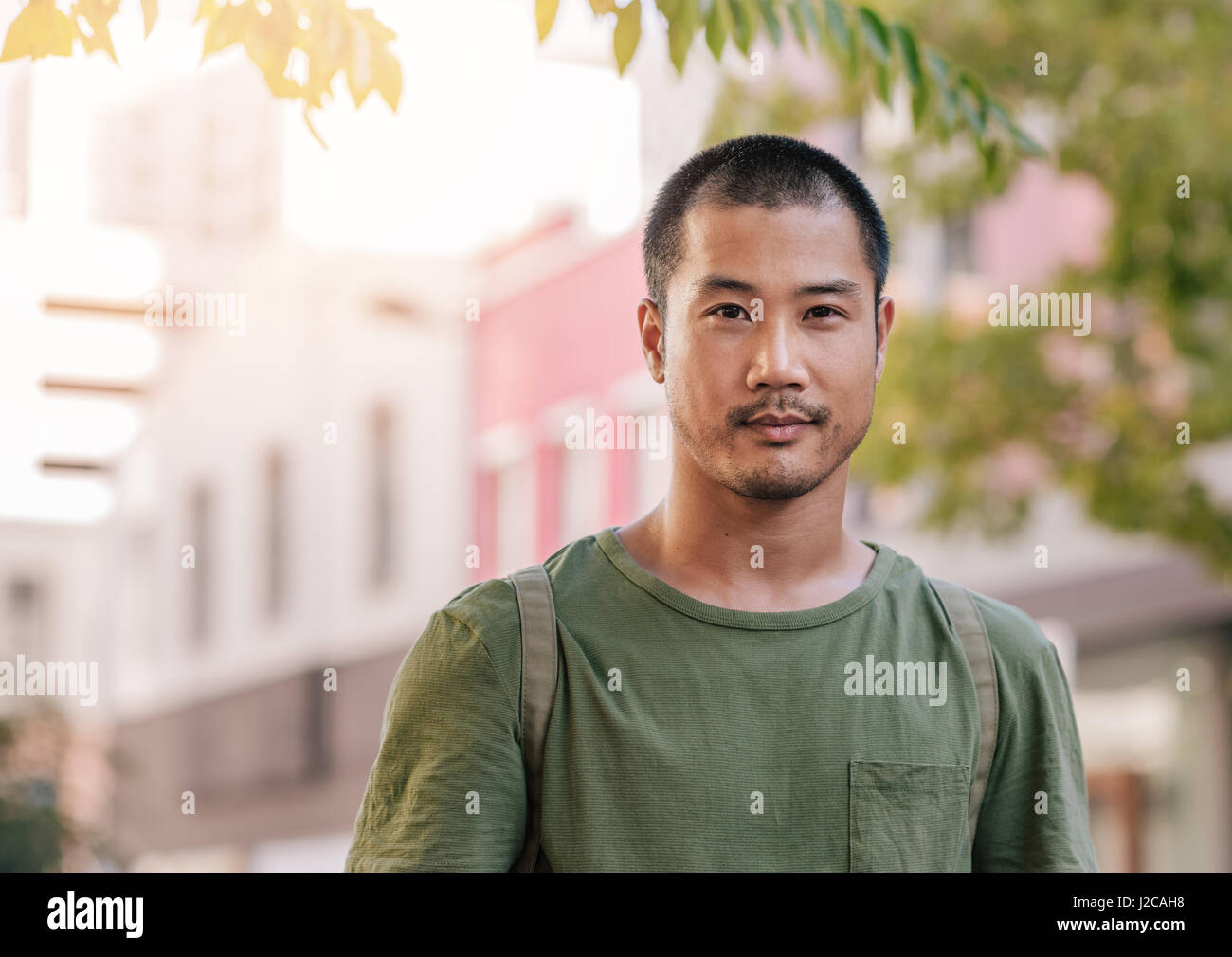 Fiducioso giovane uomo asiatico in piedi su una strada di città Foto Stock