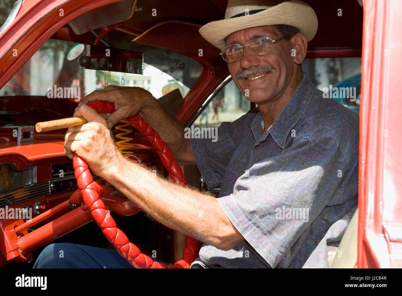 Uomo cubano con un sigaro seduti dentro il suo classico americano auto, Havana, Cuba. Foto Stock