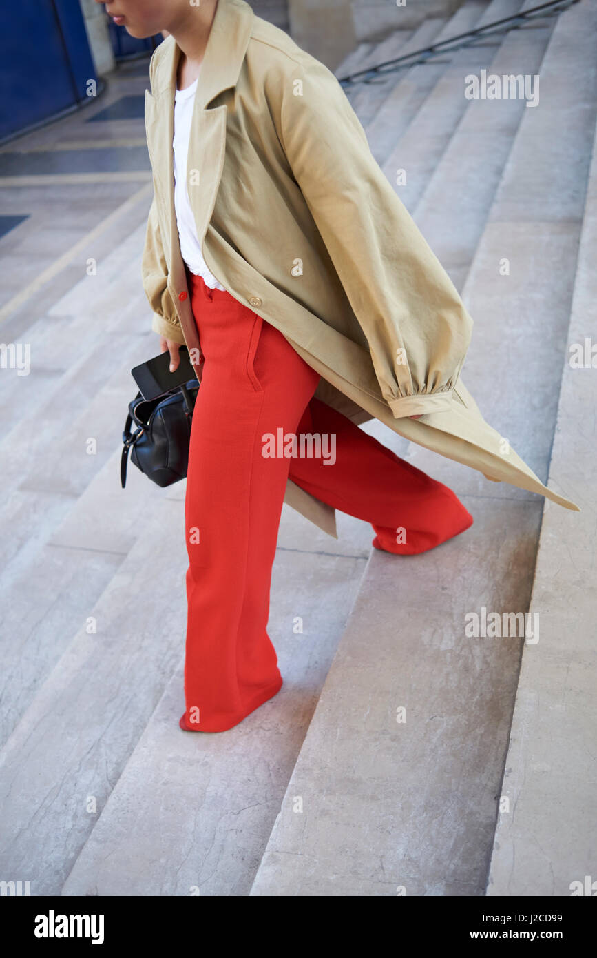 Donna in cappotto oversize e pantaloni svasati, raccolto verticale Foto Stock