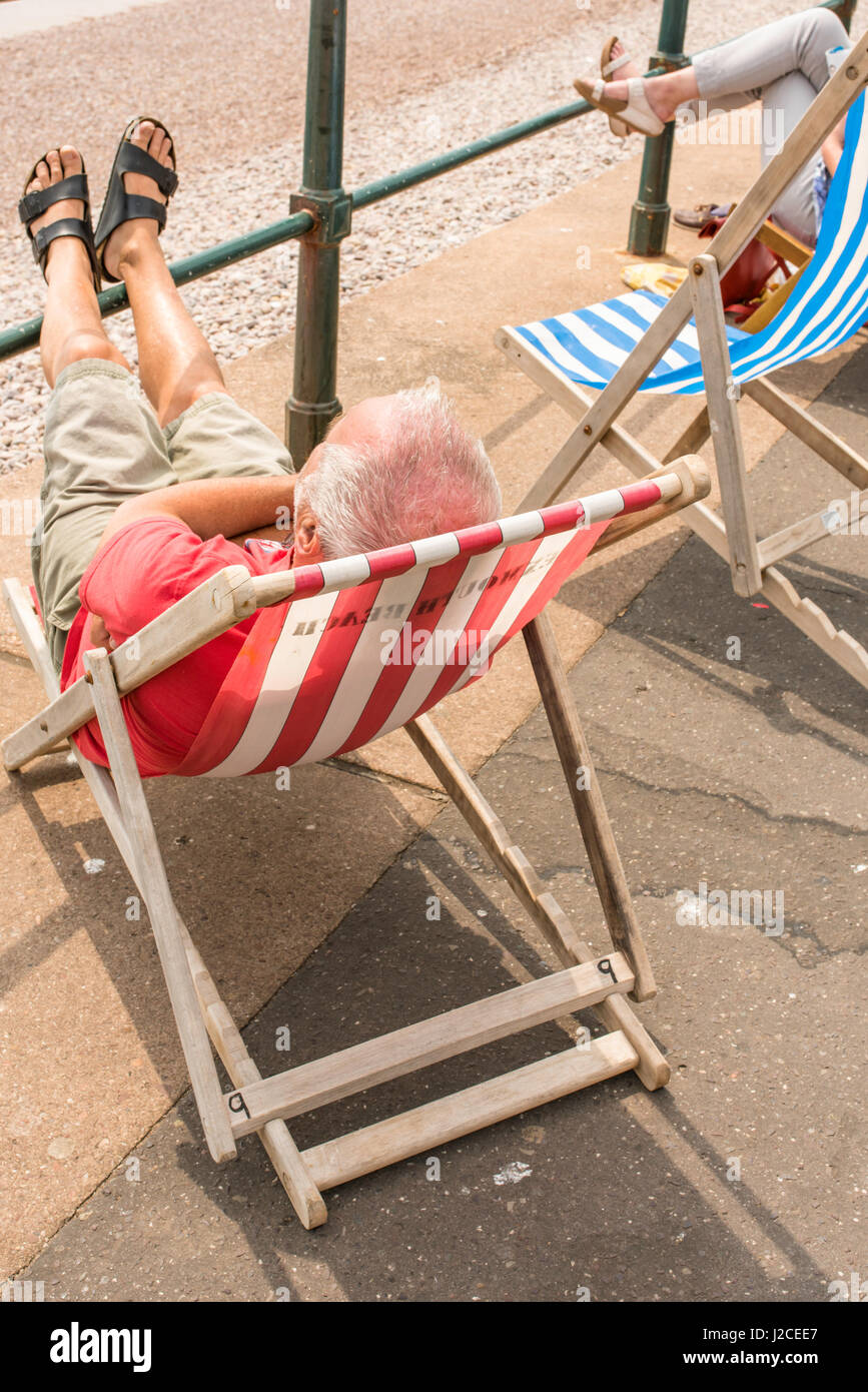 Persone in sedie a sdraio sul lungomare a Sidmouth in una giornata di sole. Foto Stock