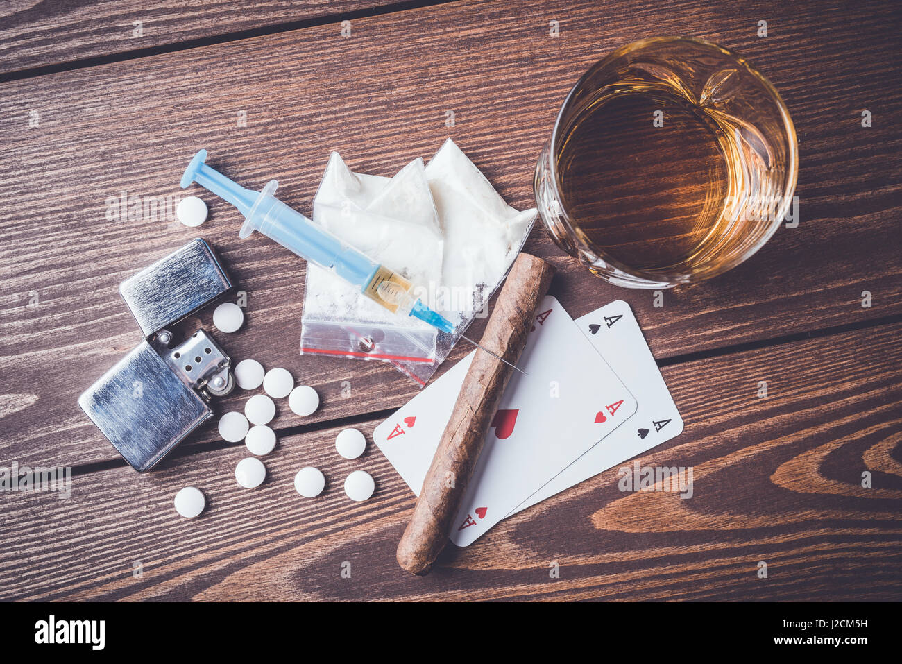 Droghe pesanti con le pillole, giocando a carte, siringa e alcool sul tavolo di legno Foto Stock