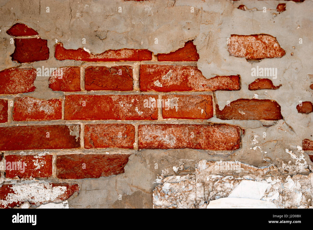 Abbandonata la parete in mattoni parzialmente ricoperto con il cemento grigio gesso Foto Stock