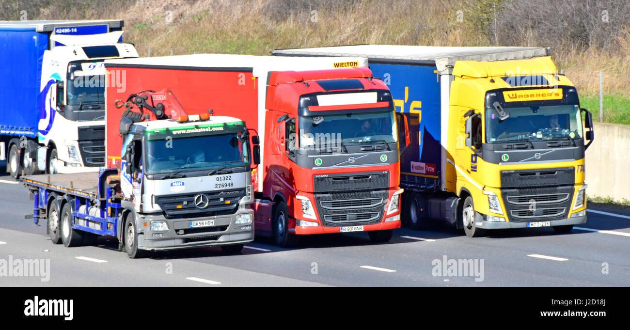 M25 Autostrada del traffico del Regno Unito carrello camionista guida nella corsia di sorpasso tre due stranieri autocarri continentale nella trafficata traffico autostradale quattro lane sezione Foto Stock