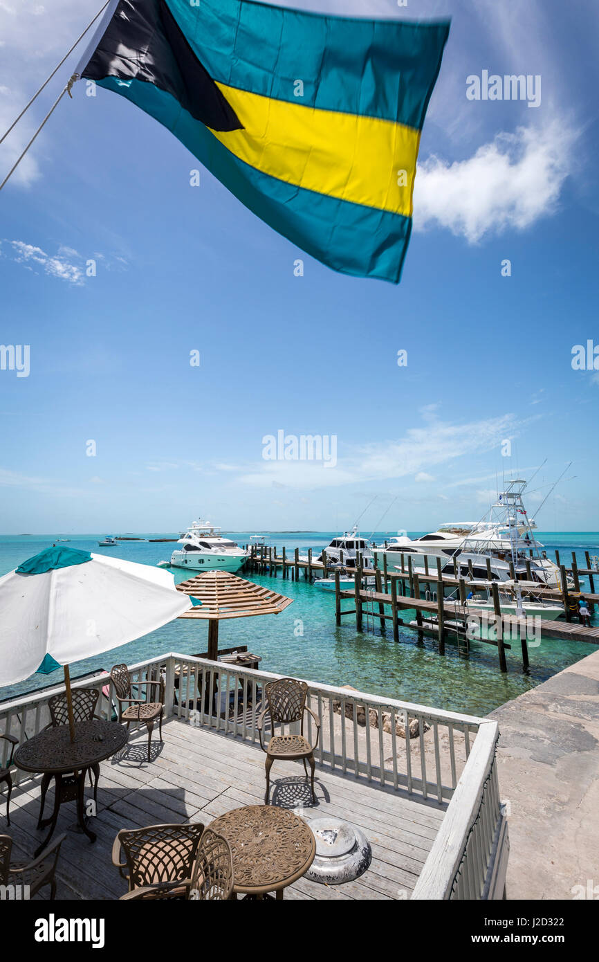 La bandiera delle Bahamas onde sopra le chiare acque blu e yacht a Staniel Cay Yacht Club su Staniel Cay, Exuma, Bahamas. Foto Stock
