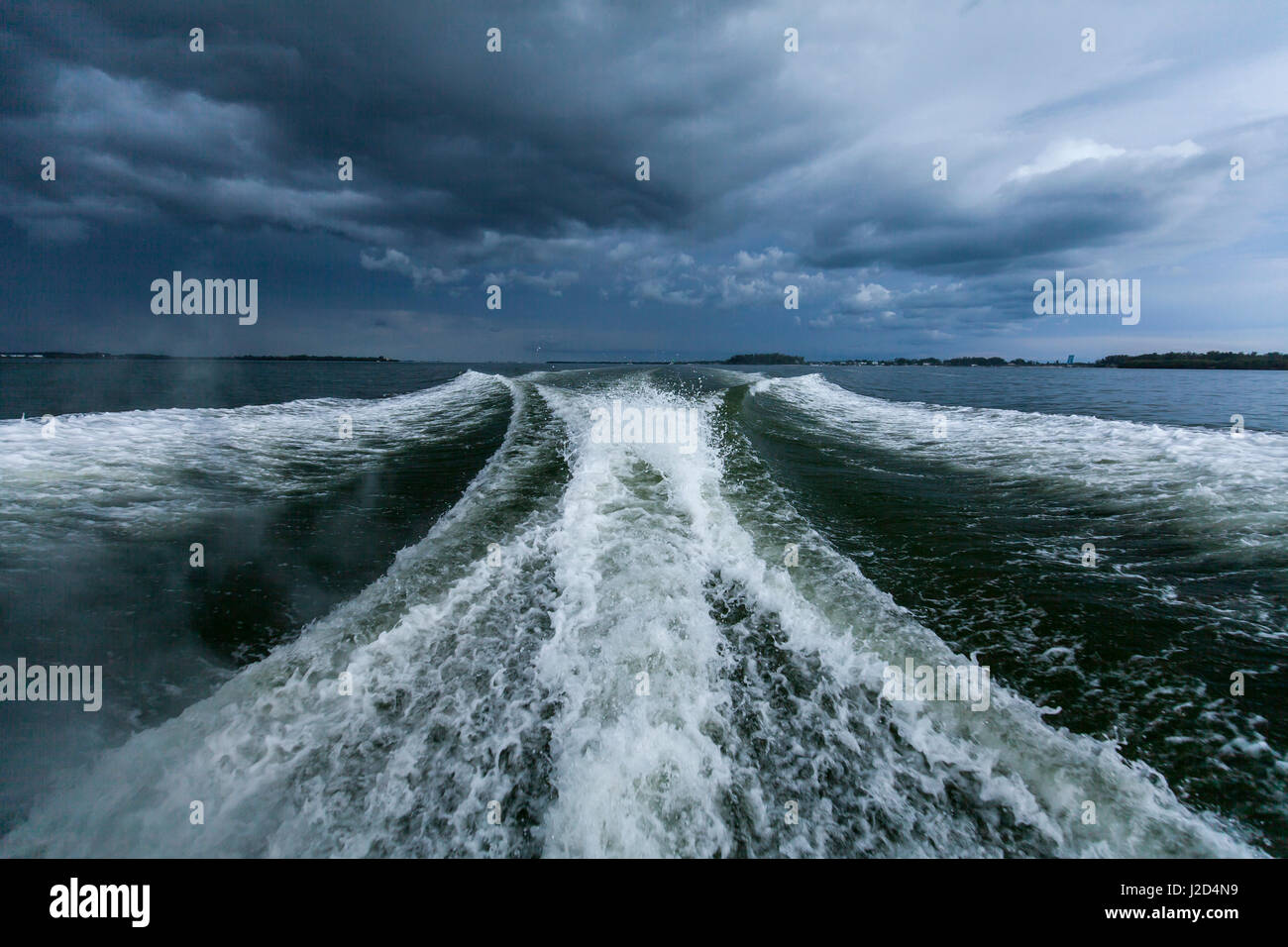 Guardando indietro a una pesca sportiva della barca wake durante la guida al largo di Anna Maria Island con nuvole temporalesche in background. Foto Stock