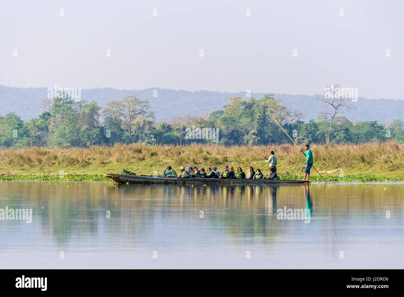 Una barca con i turisti è galleggiante sul fiume rapti in Chitwan il parco nazionale Foto Stock