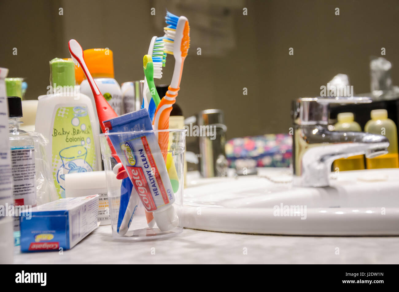 Articoli da toeletta intorno a un lavandino del bagno in una camera di hotel. Foto Stock