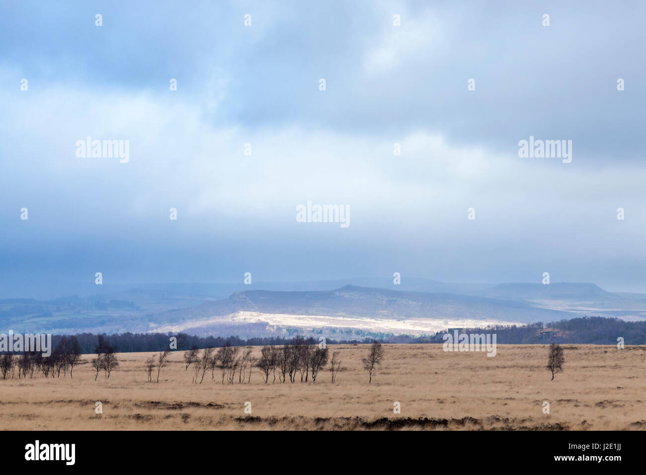 Condizioni atmosferiche variabili in inverno con le nuvole scure e la luce del sole su i Mori. Stoke piana, Derbyshire, Parco Nazionale di Peak District, England, Regno Unito Foto Stock