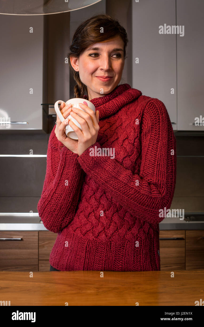 Donna sorridente coppa di ritegno con Cuori rosa in cucina Foto Stock
