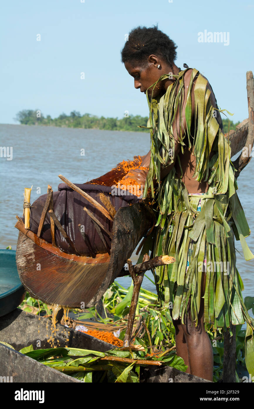 La Melanesia, Papua Nuova Guinea, fiume Sepik, villaggio di Kopar. Donna in foglia di palma abbigliamento lungo il Riverfront lavaggio e lavorazione sago palm la pasta utilizzata per i tipici cibi amidacei fiocco. Foto Stock