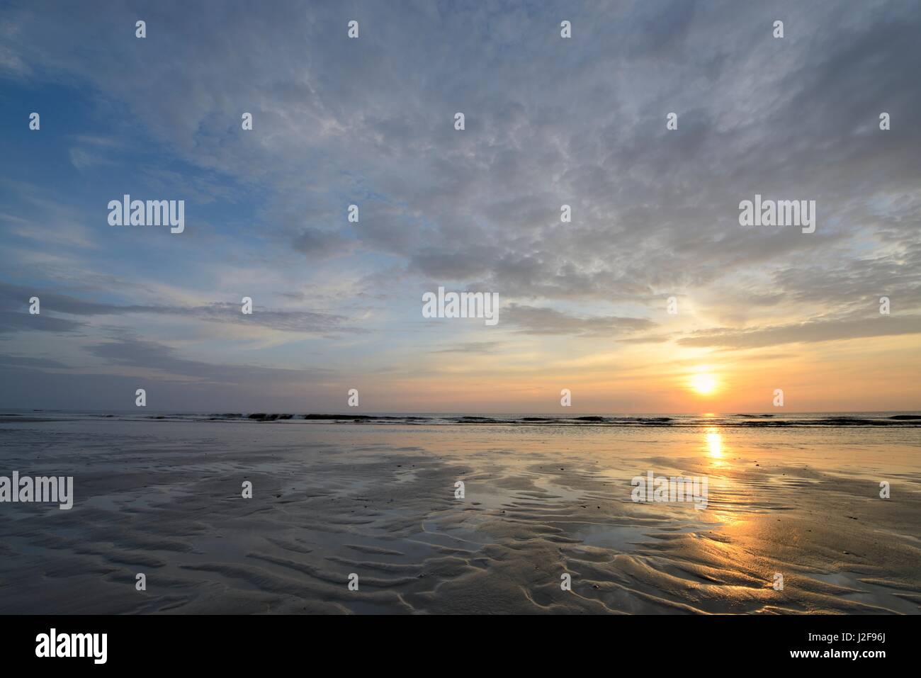 La luce calda del sole che riflette sulla sabbia e acqua durante il tramonto sulla spiaggia di Julianadorp Foto Stock