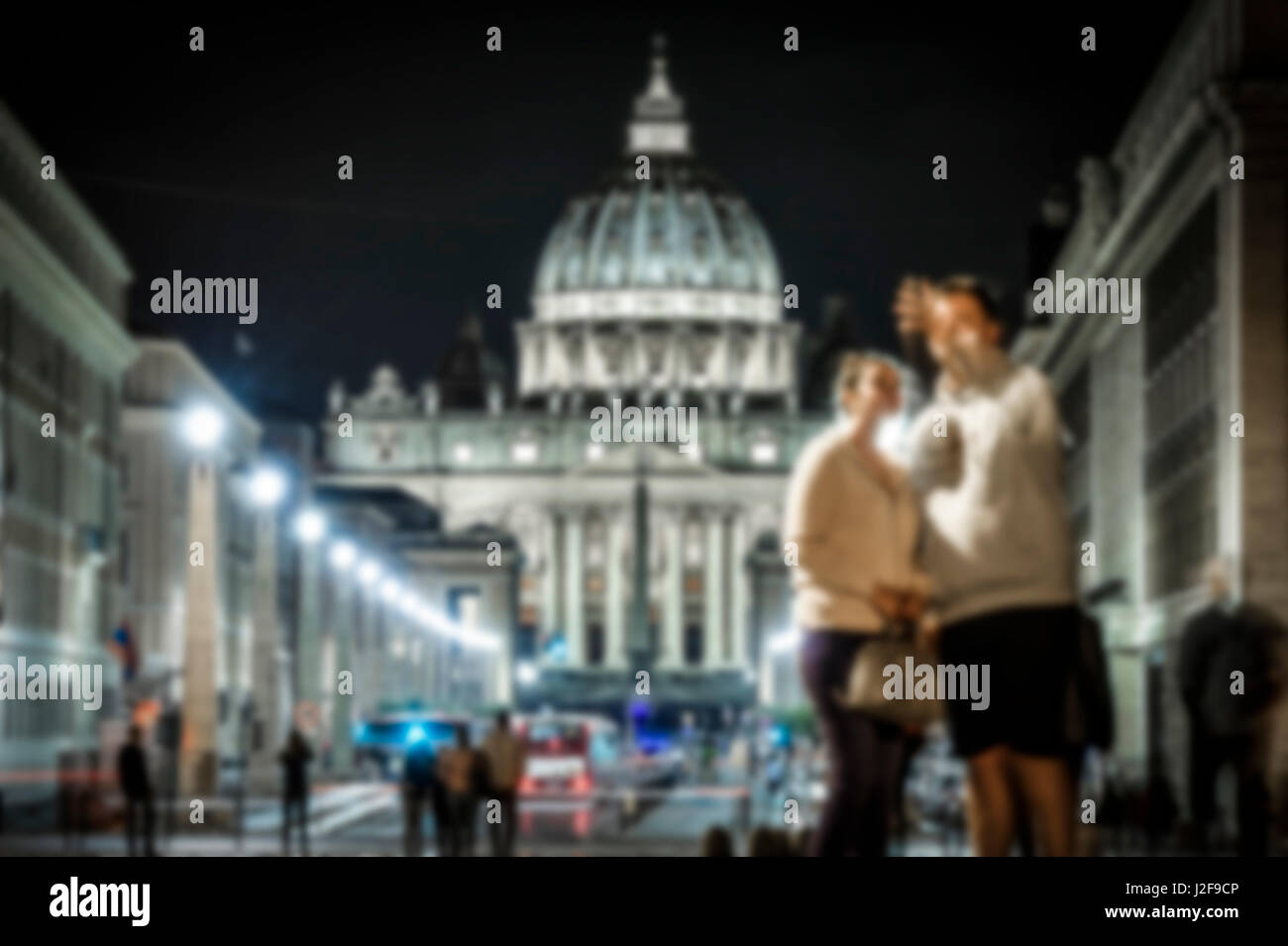 Coppia sfocata è tenuto selfie davanti la Basilica di San Pietro e Via della Conciliazione di notte Foto Stock