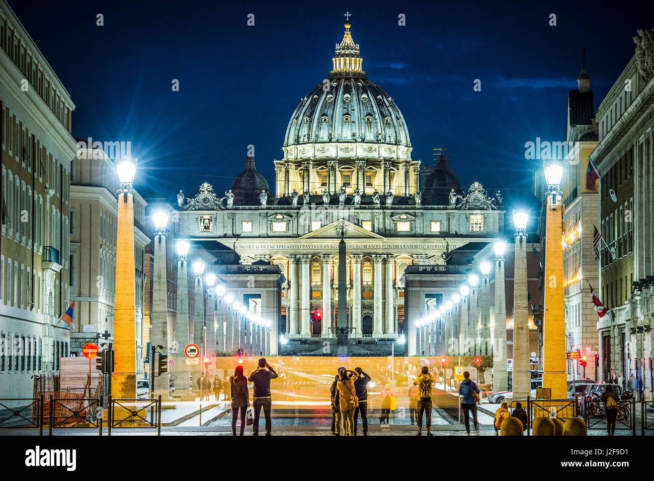 Vista illuminata Basilica di San Pietro, Via della Conciliazione e sentieri di luce delle vetture in Roma, Italia Foto Stock