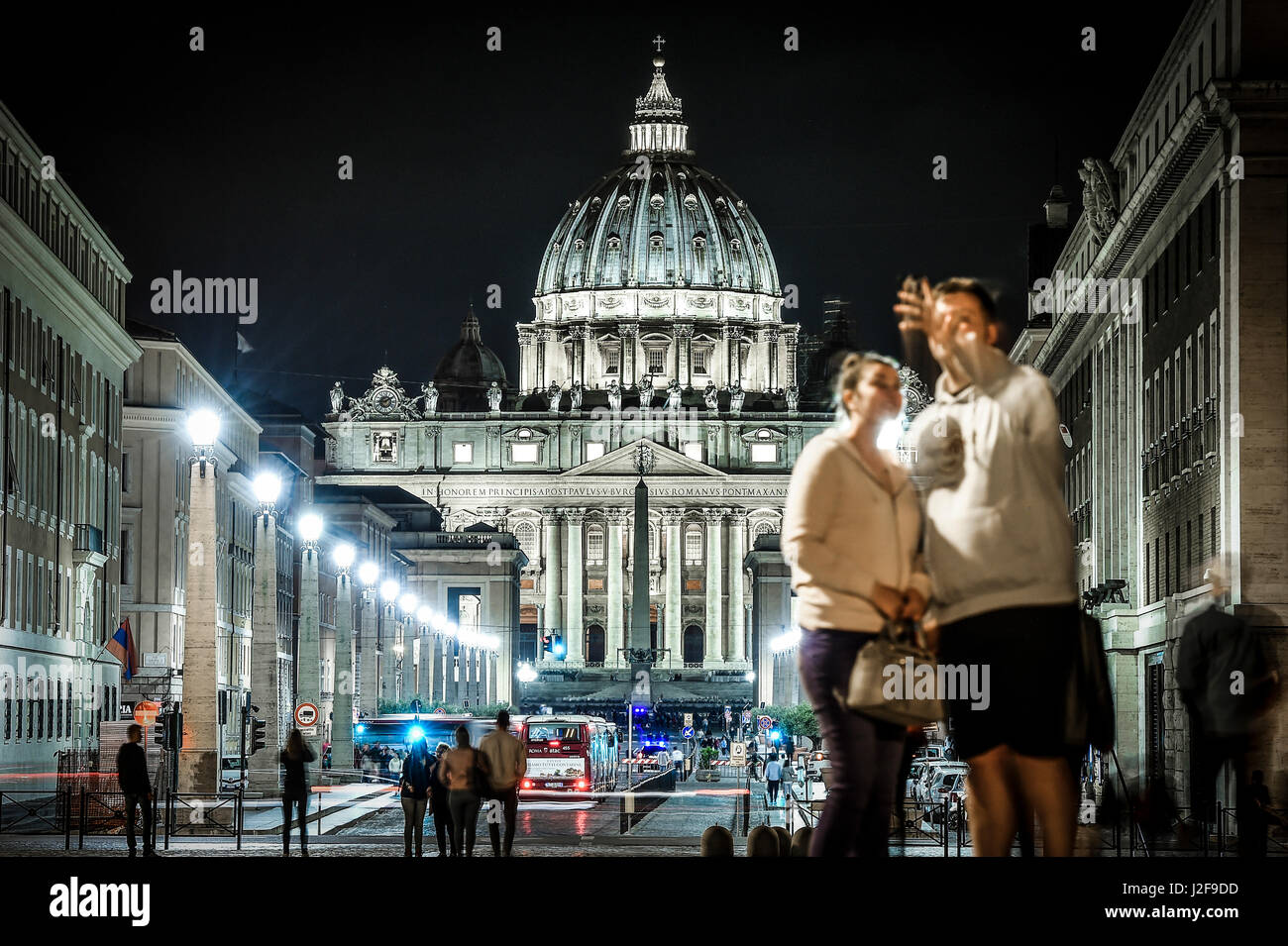 Coppia sfocata è tenuto selfie davanti la Basilica di San Pietro e Via della Conciliazione di notte (sfocata) Foto Stock