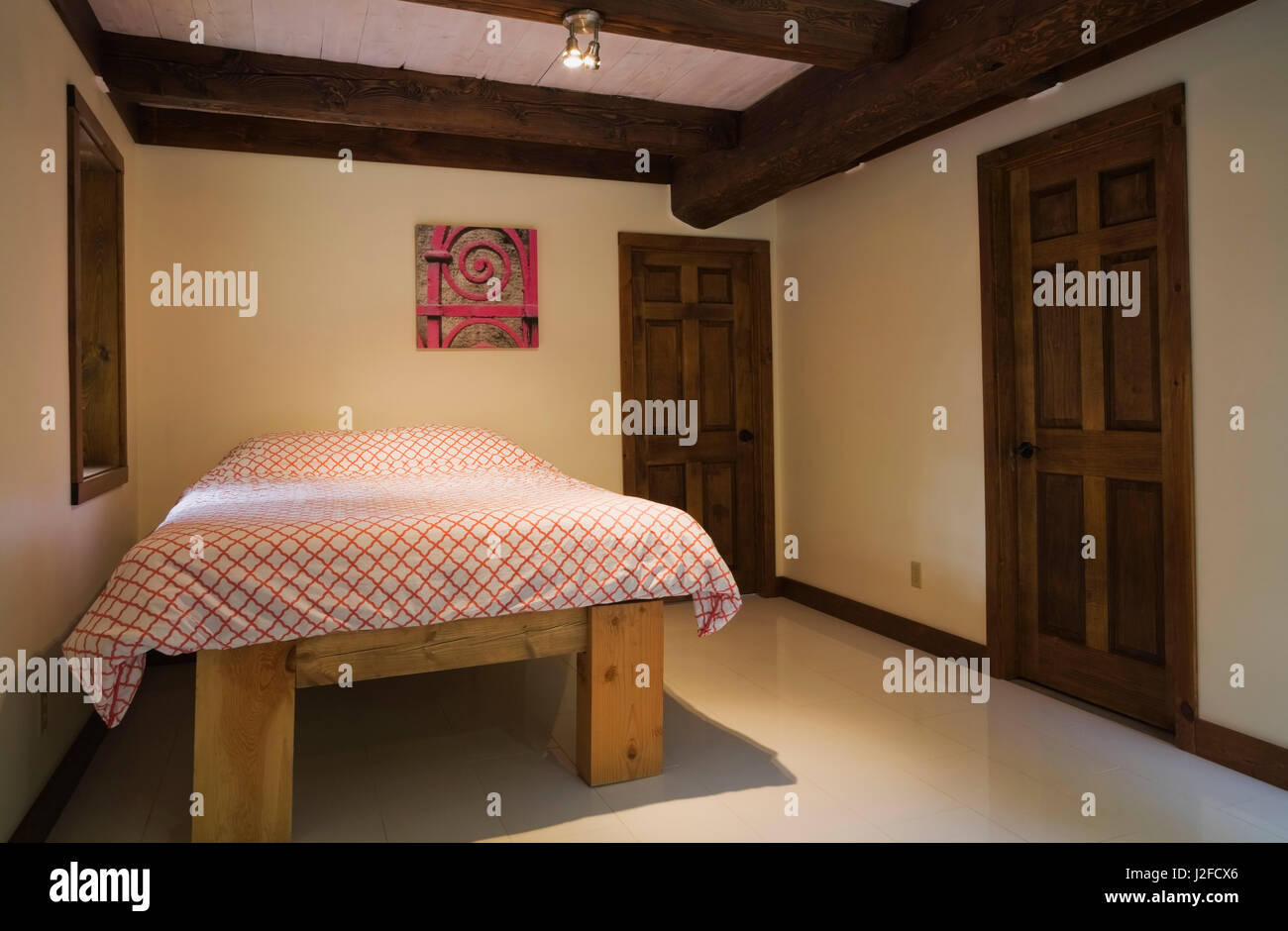 Letto queen size sul telaio in legno nella camera da letto degli ospiti all'interno di un cottage in stile casa di registro Foto Stock