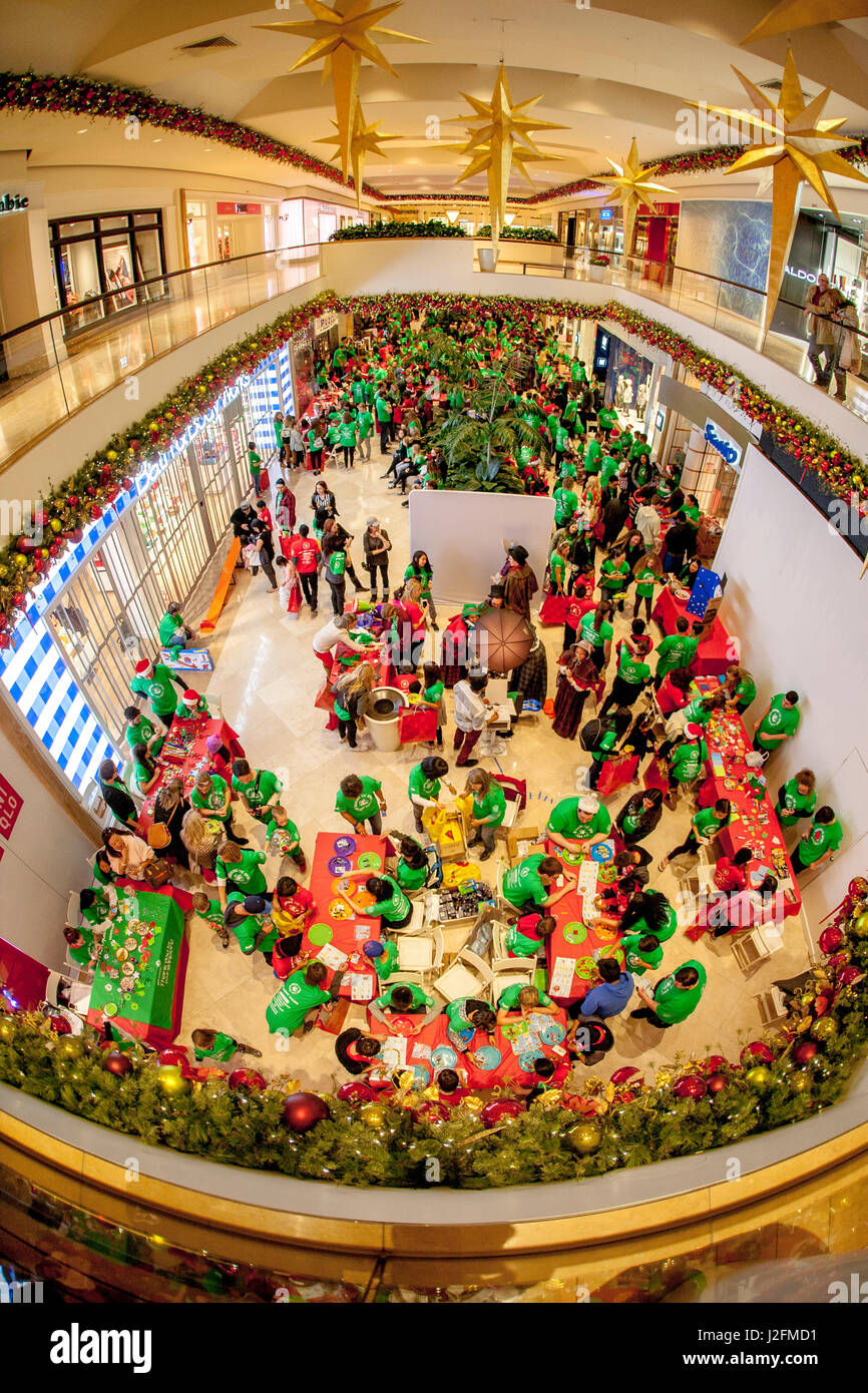 Natale multirazziale celebranti, molti in costume, affollano una vacanza annuale festival presso un lussuoso shopping mall in Costa Mesa, CA. Nota fiera artigianale in primo piano. Foto Stock