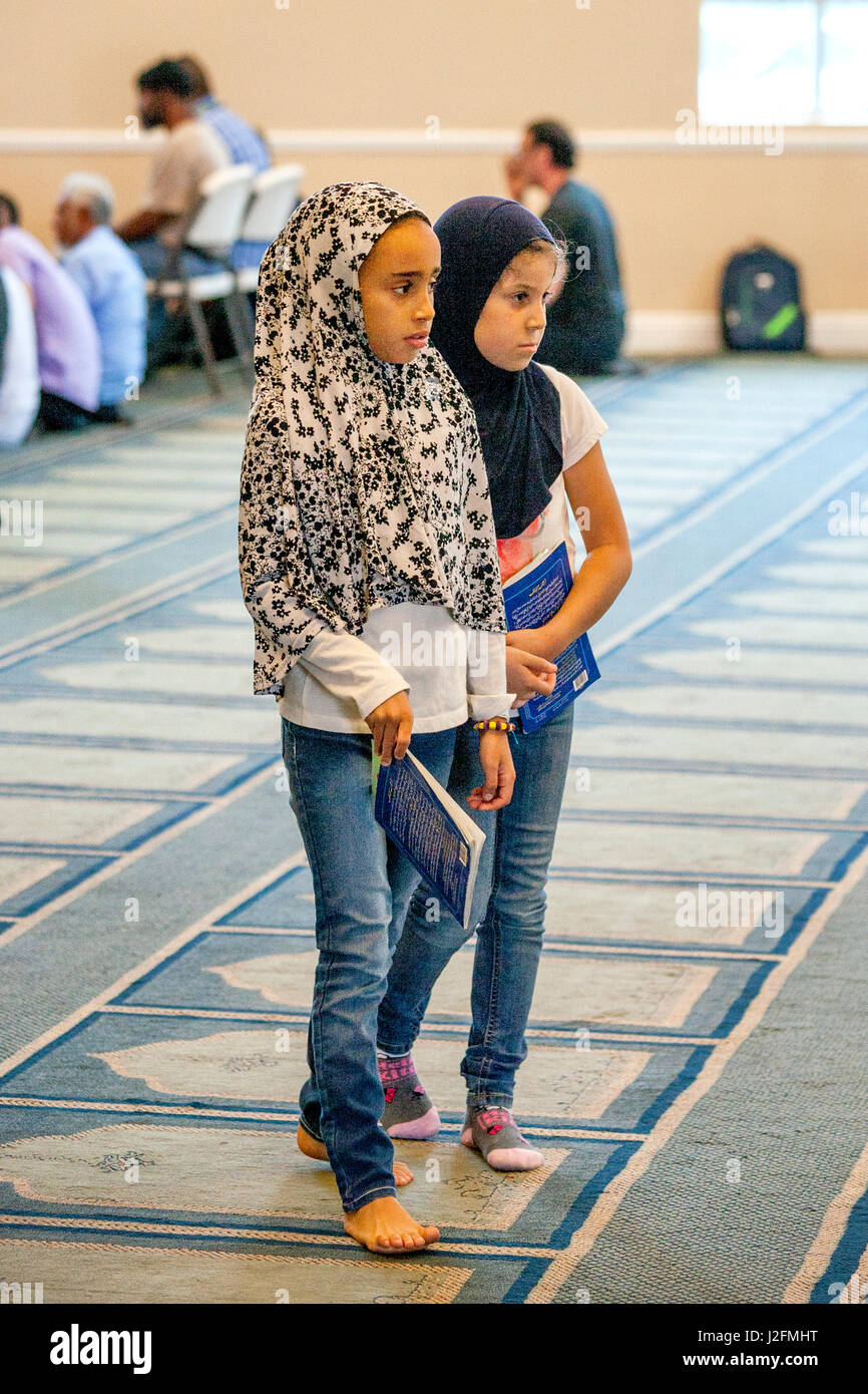 Indossando un hijabs o testa sciarpe, due ragazze musulmane di attendere per  il sermone o Khutbah per avviare durante i servizi religiosi a un Anaheim,  CA, la moschea. Nota tappeto con modello