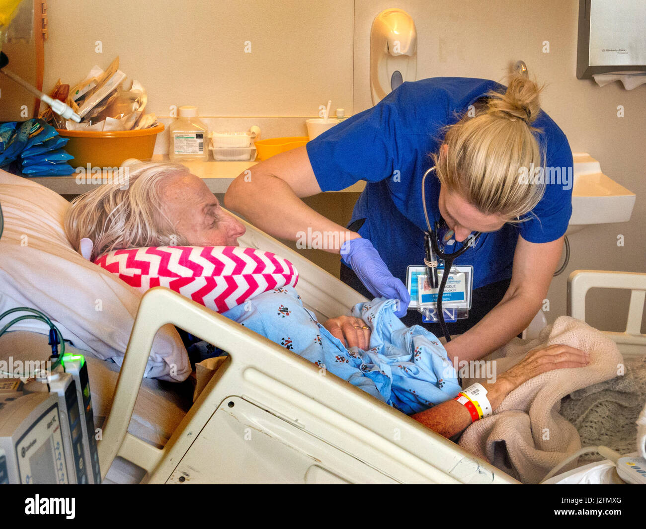 Un infermiere esamina una chirurgia di recupero del paziente avvolto in corrispondenza di un Irvine, CA, ospedale. Nota cuscino cervicale. Foto Stock
