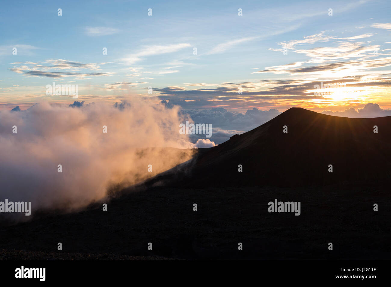 Il tramonto visto dalla cima del Mauna Kea vulcano sulla Big Island delle Hawaii con pietra lavica in primo piano Foto Stock