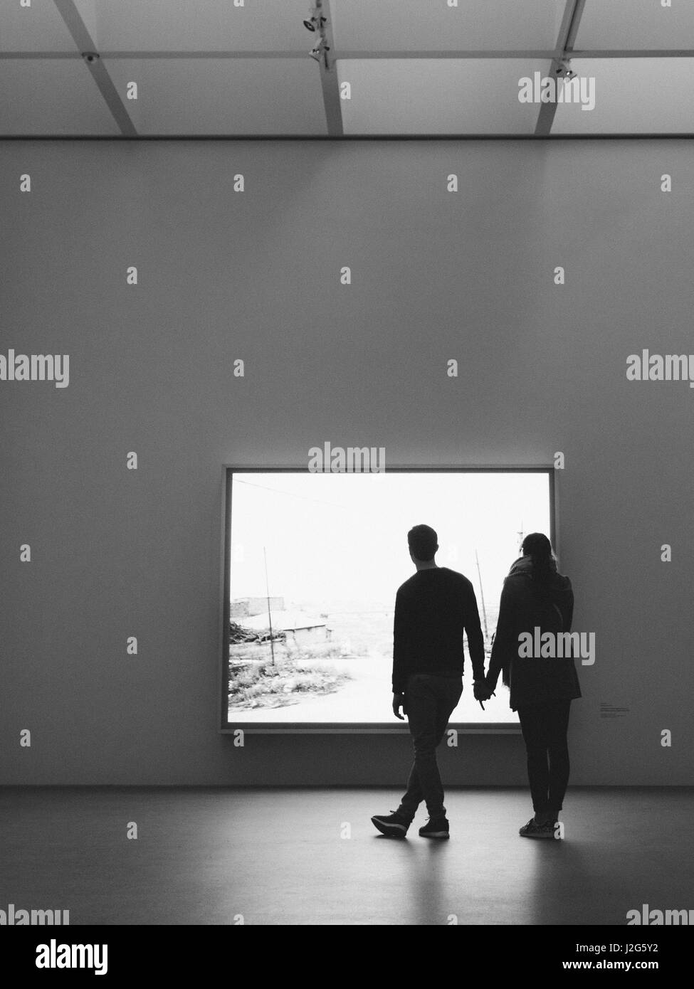 Una silhouette di un maschio e femmina giovane guardando una mostra in un museo di arte Foto Stock