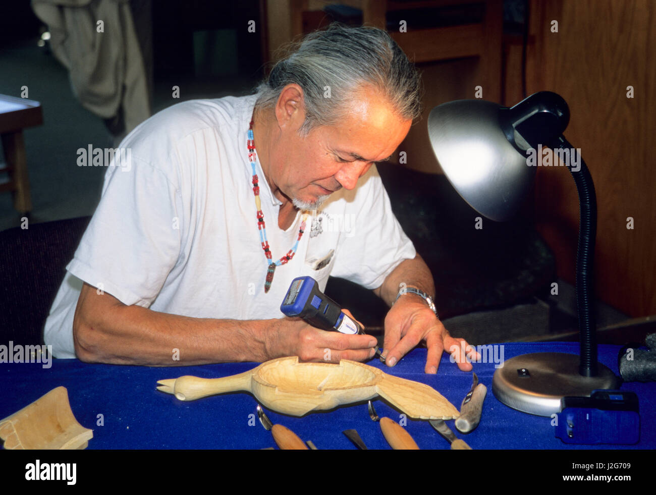 Athabaskan tradizionale intagliatore di legno dimostra come egli si avvale di moderni strumenti come un dremel a intagliare bellissimi pezzi di artigianato di legno. Fairbanks Alaska Foto Stock