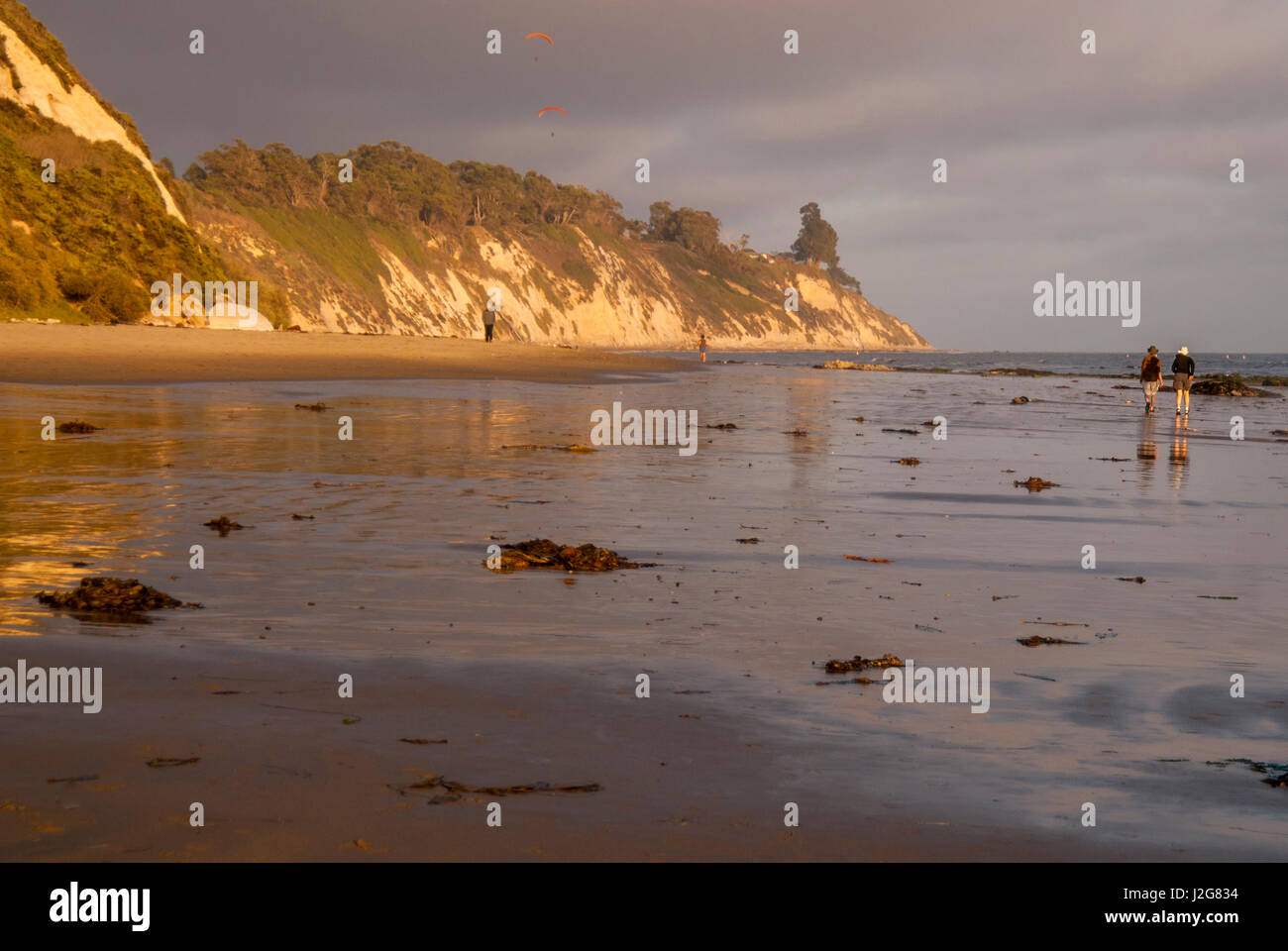 Stati Uniti, California, Santa Barbara, Hendry Spiaggia del giovane a piedi attraverso la bassa marea, tramonto Foto Stock