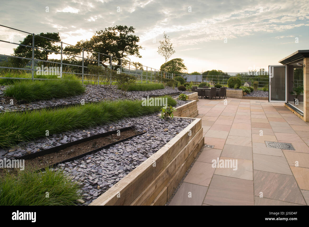 Bella e paesaggistici, giardino privato con un design contemporaneo, patio, arbusti ed erbe in linee sul bordo in rilievo - Yorkshire, Inghilterra, Regno Unito. Foto Stock