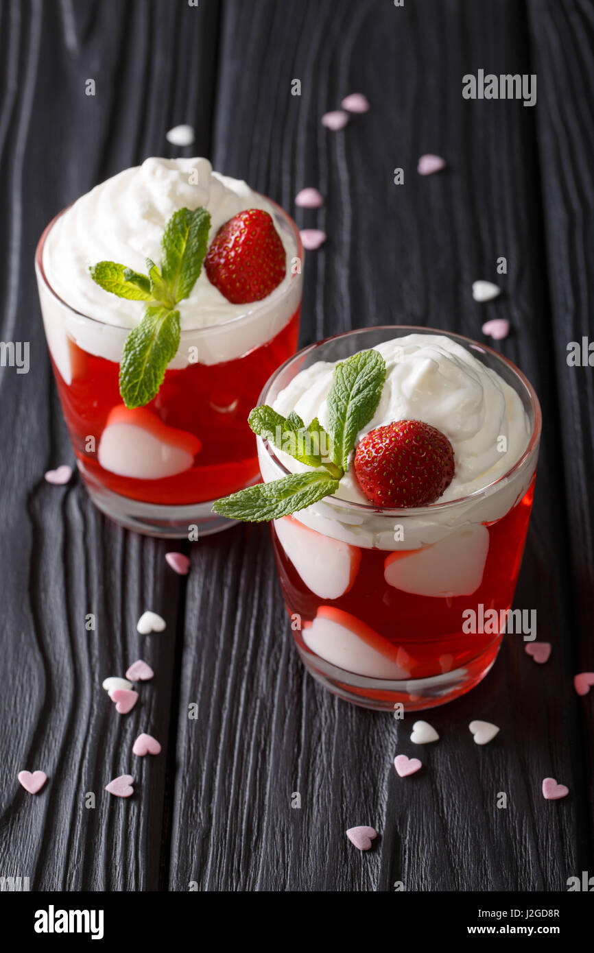 Bellissimo dessert di fragole, decorata con cuori e menta fresca vicino fino in un bicchiere sulla tavola verticale. Foto Stock