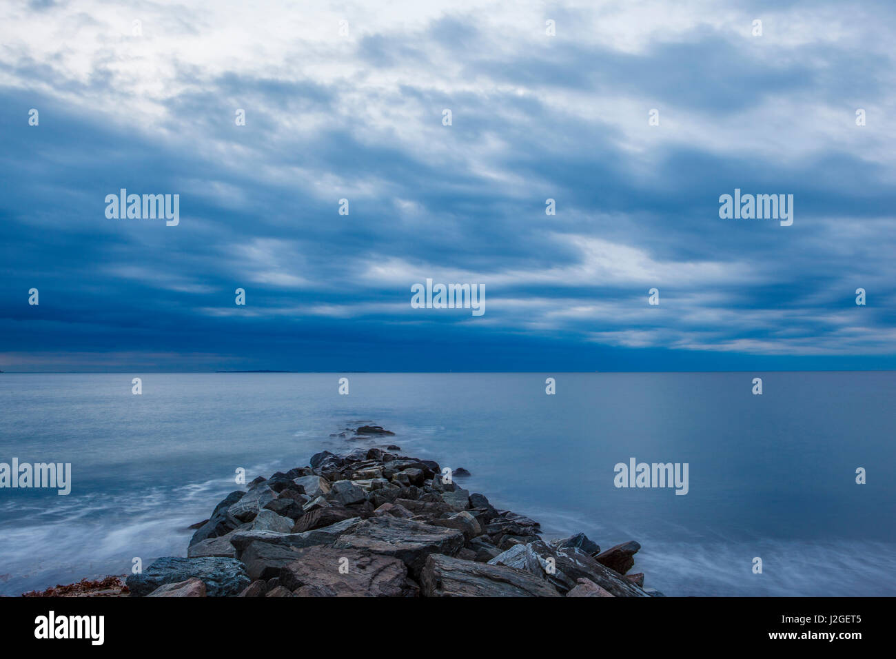 Un nuvoloso alba oltre il frangiflutti a Wallis Sands State Park in segale, New Hampshire. Foto Stock