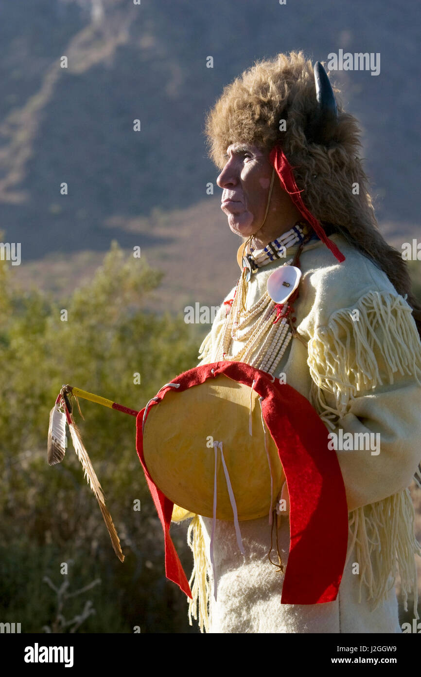 Native American uomo della Nazione Sioux vestita in un tradizionale regalia e i bisonti copricapo detiene una medicina stick e di scudo. (MR) Foto Stock