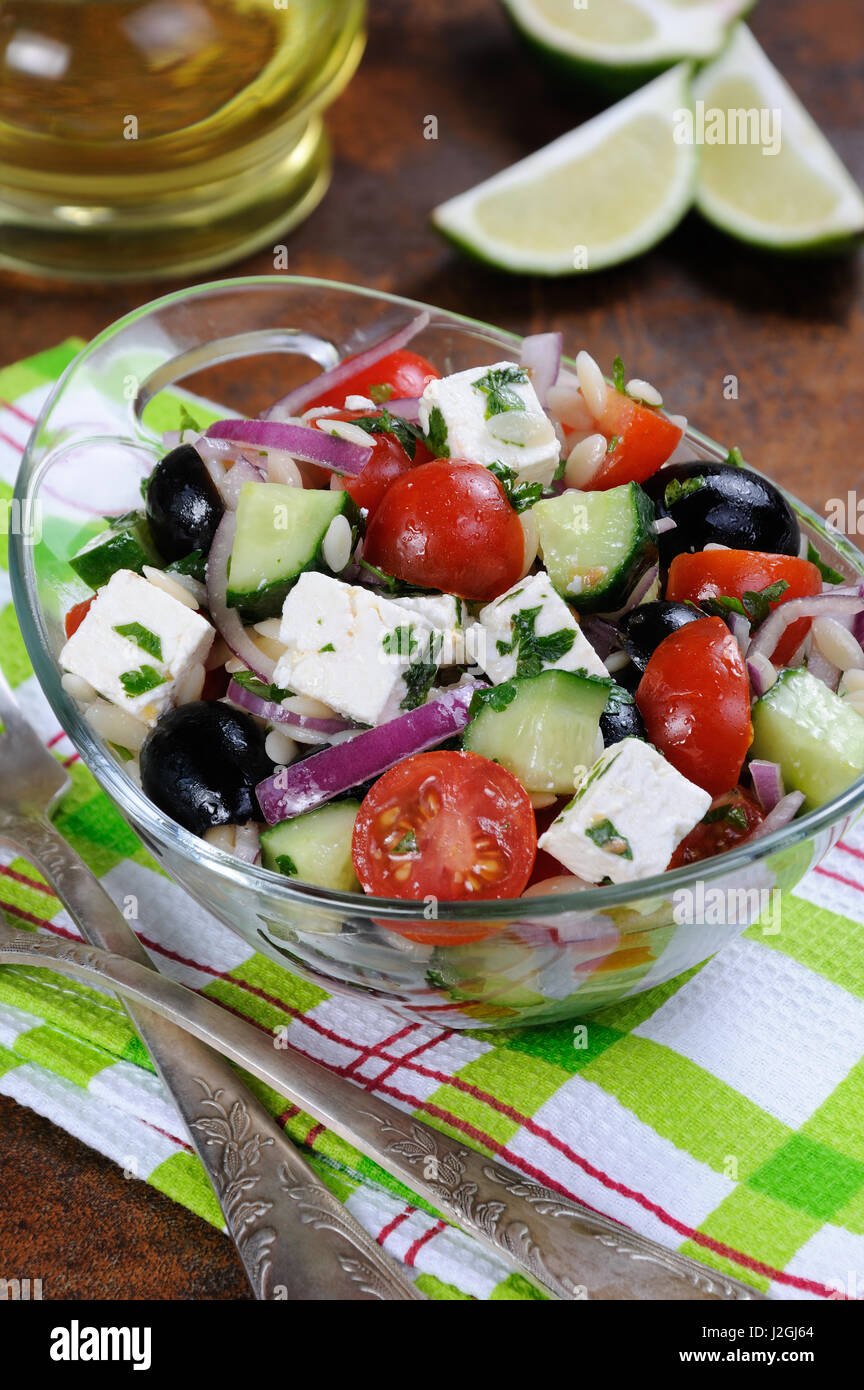 Insalata greca di pasta orzo con nero oliva, cipolla rossa e il cetriolo e i pomodori ciliegia, feta e erbe aromatiche Foto Stock