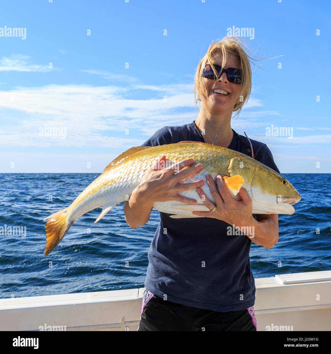 Una femmina di pescatore mantenendo la sua cattura di un grande tamburo rosso. Foto Stock