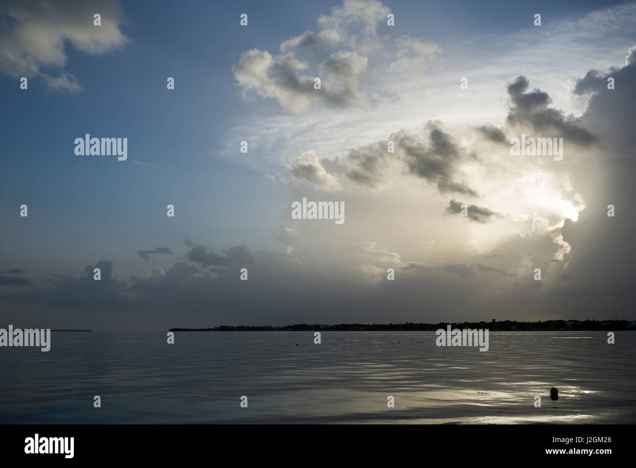 Sunray brillare attraverso le nuvole sopra il tasto bacchetta di caricamento con acqua calma e trappole di astice in primo piano nella Florida Keys. Foto Stock