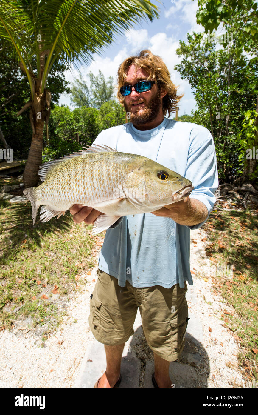 Un barbuto pescatore visualizza un appena catturati Mangrove Snapper sulla bacchetta di caricamento chiave, Florida. Foto Stock