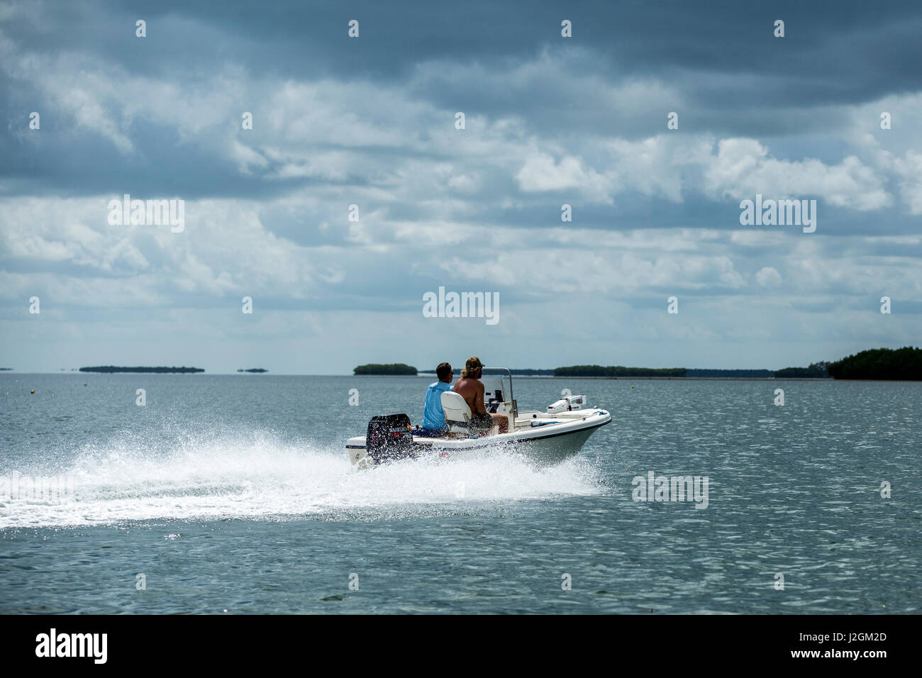 I pescatori guidare la loro barca in fondali di pesca in Florida Bay a nord della bacchetta di caricamento chiave, Florida con calma acqua e cielo nuvoloso in background Foto Stock