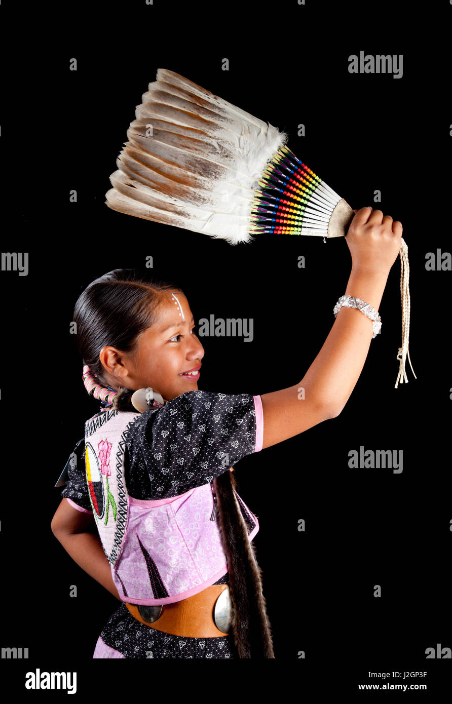 Shoshone tradizionale Pow Wow ballerino, Aarora Piper, dieci anni, vestito di danza regalia detiene una ventola di piume su sfondo nero Foto Stock