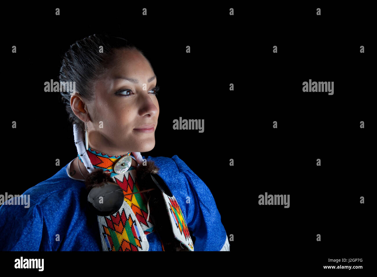 Tradizionale ragazza adolescente, Challis Baldwin (Shoshone-Bannock), vestita di Pow Wow jingle Abito danzatrice e beadwork pone su uno sfondo nero. Foto Stock
