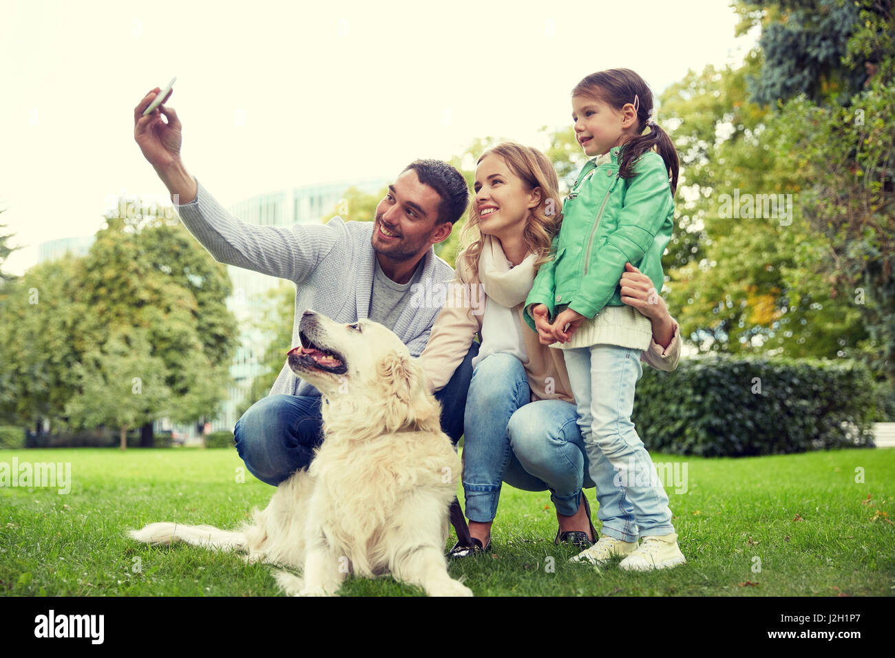 La famiglia felice con il cane tenendo selfie tramite smartphone Foto Stock