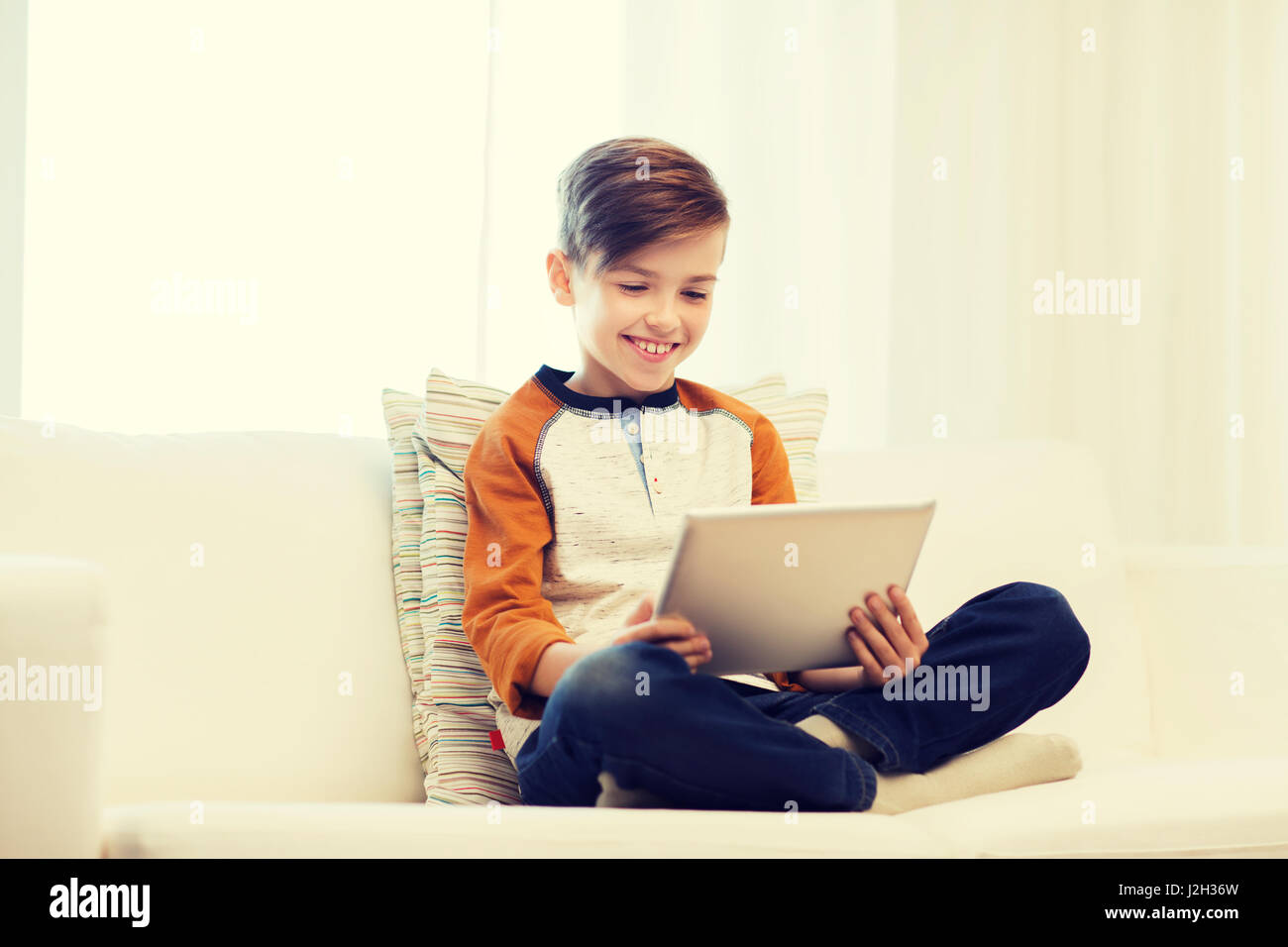 Ragazzo sorridente con il tablet pc a casa Foto Stock
